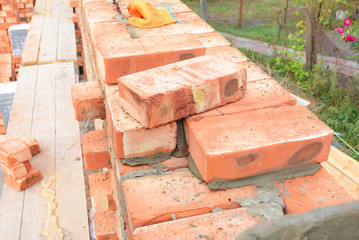 Bricklaying, Brickwork. Bricklaying on House Construction Site. Building Home wall from Bricks. Bricklayer Worker Installing Red Blocks and Caulking Brick Masonry Joints Exterior Wall.