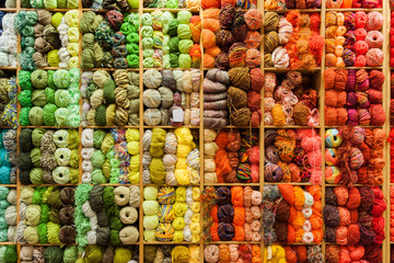 Front view of a closet full of coiled wool bunches or skein, order in a color gradient from cold to warm.