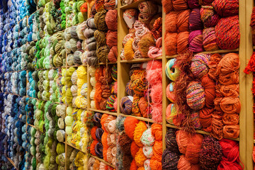 Side view of a closet full of coiled wool bunches or skein, order in a color gradient from cold to warm.