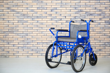 Blue wheelchair near brick wall indoors