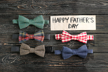 Different bow ties and greeting card on wooden background. Father's day composition