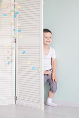 Fototapeta na wymiar happy kid behind door. the boy plays. He hides behind the white door