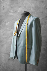 Custom-made suit on mannequin against grey background
