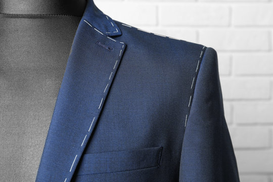Semi-ready suit on mannequin against brick wall background, closeup