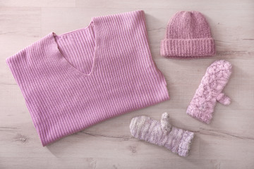 Warm knitted clothes on wooden background. Seasonal female wardrobe