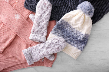 Warm knitted clothes on wooden background. Seasonal female wardrobe