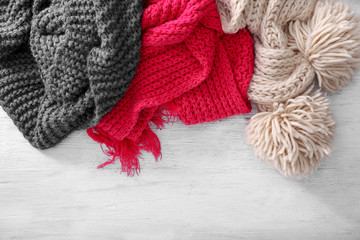 Fototapeta na wymiar Color knitted scarves on wooden background. Seasonal female wardrobe
