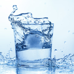 Ice drops in a glass of water with a splash