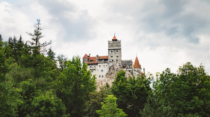 Fototapeta na wymiar Bran or Dracula Castle in Transylvania, Romania. The castle is located on top of a mountain under a gloomy cloudy sky