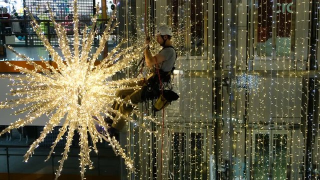 Industrial climber mounts Christmas decorations in the unsupported space in the shopping center