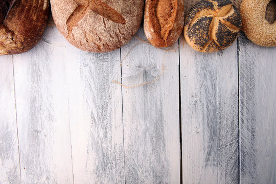 Different kinds of bread and bread rolls on wooen backgroundKitchen or bakery poster design