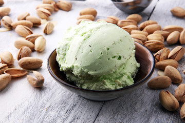 scoop of pistachio ice cream with pistachios on wooden background