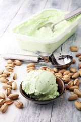 scoop of pistachio ice cream with pistachios on wooden background