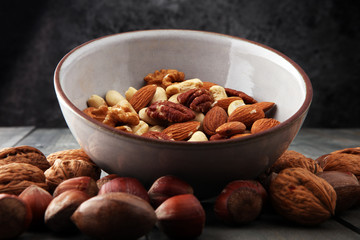 Fototapeta na wymiar bowl with mixed nuts on wooden background. Healthy food and snack. Walnut, pecan, almonds, hazelnuts and cashews.