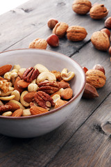 bowl with mixed nuts on wooden background. Healthy food and snack. Walnut, pecan, almonds, hazelnuts and cashews.