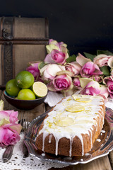 cupcake with lime and white cream on an old tray, pink roses and a wooden background