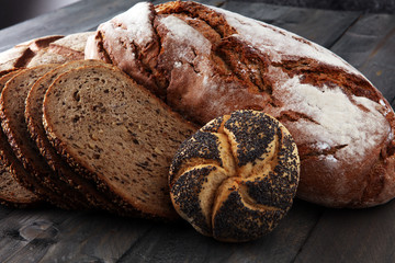 Different kinds of bread and bread rolls on wooden table. Kitchen or bakery poster design