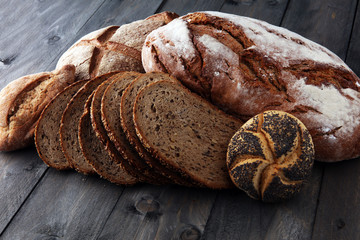 Different kinds of bread and bread rolls on wooden table. Kitchen or bakery poster design