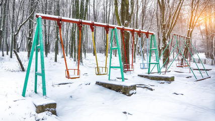 Fototapeta na wymiar Empty swing in winter time with snow