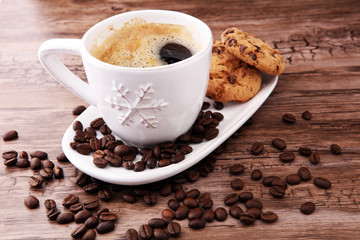Coffee cup with chocolate cookies and coffee beans on wooden background