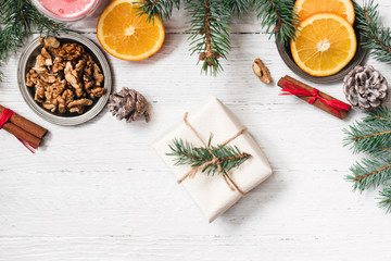 Orange in the cut, cinnamon, walnut on a white background. Branches of Christmas trees, gifts and bumps. A flat place, a place to copy, a top view. Holidays.
