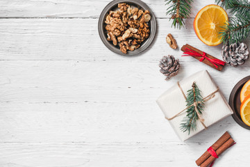 Orange in the cut, cinnamon, walnut on a white background. Branches of Christmas trees, gifts and bumps. A flat place, a place to copy, a top view. Holidays.