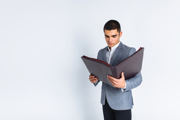 Handsome man with folder man reading a menu, a stylish business guy in suit in Studio on white background