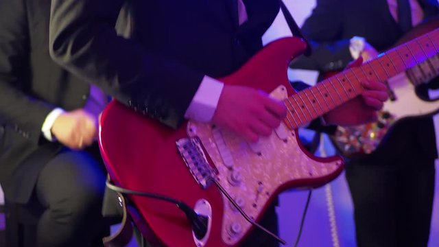 Man playing electric guitar on a stage, musical concert close-up view