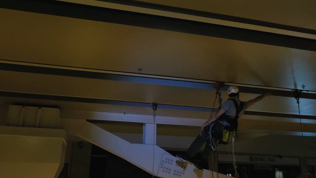 Industrial climber mounts Christmas decorations in the unsupported space in the shopping center