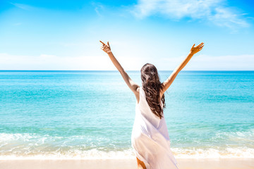 Fototapeta na wymiar Beautiful young single white woman on beach. Standing happy freedom pose relaxing, wearing white dress.