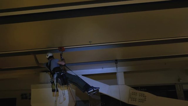 Industrial climber mounts Christmas decorations in the unsupported space in the shopping center