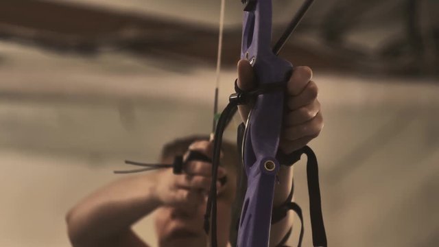 The arrow in the target. Young girl a shoots from a bow in the shooting range. Closeup.