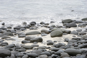 Fototapeta na wymiar Sand-Textur bei Ebbe mit schwarzen Steinen - Westfjorde / Island