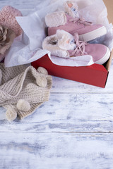 warm clothes and shoes for a little girl, in pink shades on a white wooden background
