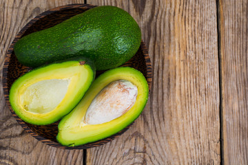 Fresh whole avocado and halves on wooden table