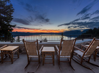 Fototapeta premium Krzesła na biegunach i stół wychodzą na wschód słońca nad jeziorem Krater