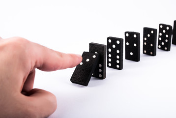 Finger push dominoes tiles and they fall isolated on a white background. Domino effect concept