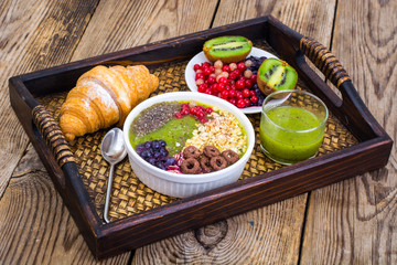 Wooden tray with fruit dishes and croissant for lunch
