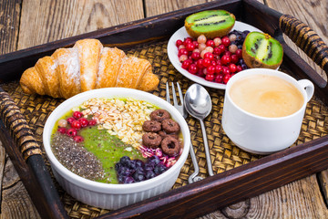 Wooden tray with fruit dishes and croissant for lunch