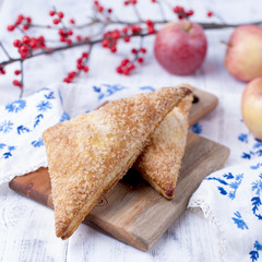 apple pies on a wooden board and white background, branch with red berries and apples