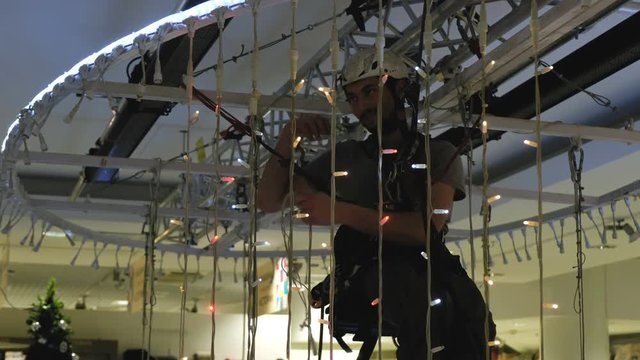 Industrial climber mounts Christmas decorations in the unsupported space in the shopping center