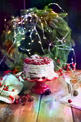 cake with red berries, glass of wine near the Christmas tree on a black background