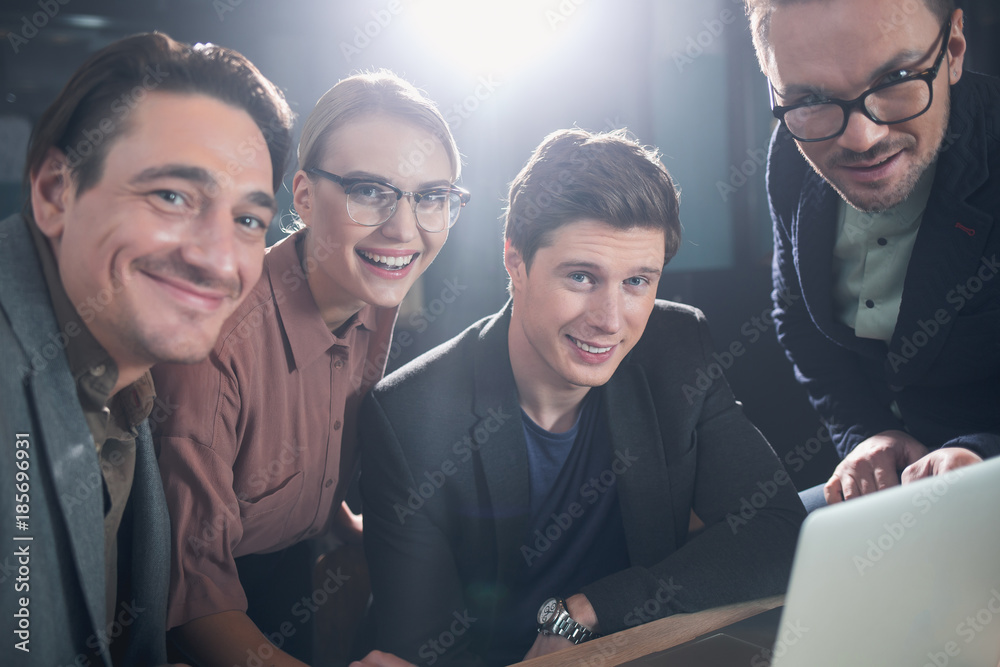 Aufkleber Portrait of cheerful males and beaming woman working with notebook computer while situating at desk in room. Profession and career concept