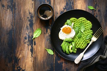 Spinach cheese waffles with fried egg and avocado.Top view with copy space.