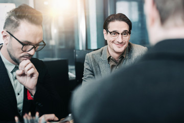 Portrait of cheerful male speaking with partner while locating at desk. Labor and conversation concept