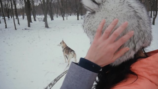 beautiful young woman playing with a dog in a winter snowy park