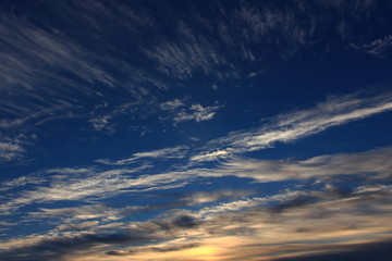 Amazing panoramic bright blue sky with light transparent clouds against the dawn of the sun making its way through the cloud
