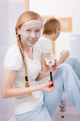 Happy young woman having mud mask on face