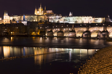 Night colorful snowy Christmas Prague Lesser Town with gothic Castle and Charles Bridge, Czech republic