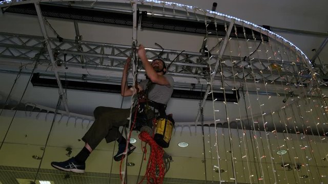 Industrial climber mounts Christmas decorations in the unsupported space in the shopping center